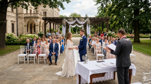 Na tym obrazie widać scenę ślubu plenerowego, prawdopodobnie w ogrodzie lub na dziedzińcu eleganckiej posiadłości